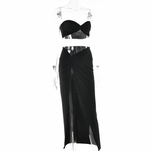 Detail of sexy black two-piece set featuring twist-front crop top and high side slit skirt