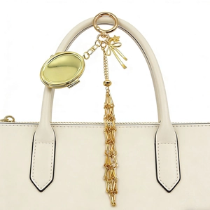 Golden keychain with pink bow, star pendant and mirror box hanging on a handbag