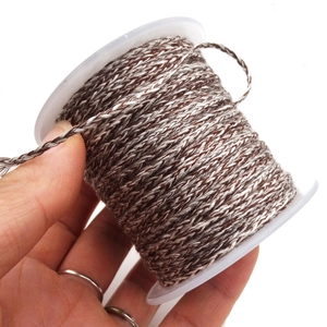 Detail of coffee and white twisted cotton cord on a spool for DIY jewelry crafts