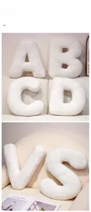 Close-up of assorted alphabet plush pillows in warm white soft sherpa fabric texture
