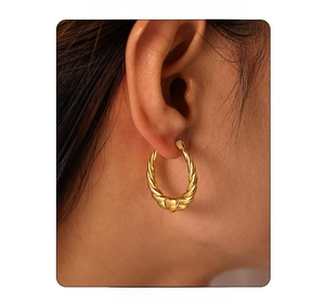 Detailed close-up of 18K gold plated spiral hoop earring with heart charm on ear