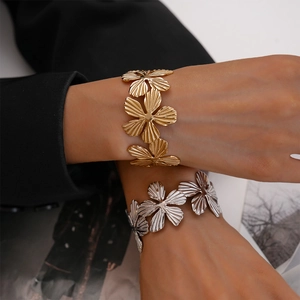Detail of two-piece textured flower open bangles in gold and silver finish on a model
