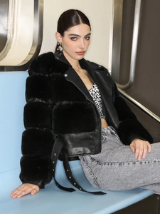 Detail of black faux fur and leather patchwork jacket with buckle belt in subway setting