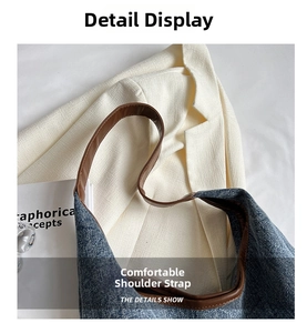 Detail of the brown leather shoulder strap on a denim tote bag with visible stitching