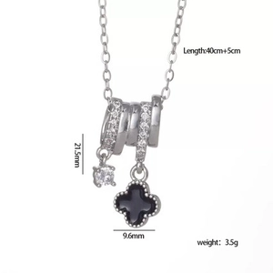 Detailed view of silver four-leaf clover necklace with black stone and zircon inlays
