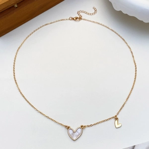 Close-up of golden heart necklace featuring a white mother of pearl inlay and small gold charm