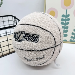 Detail of off-white plush basketball pillow with black embroidery and CE safety label