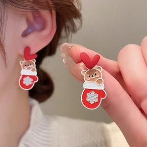 Detailed view of red heart and brown bear earrings with festive snowflake glove design