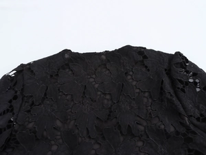 Primo piano del top in pizzo nero con intricati motivi floreali traforati sulla scollatura