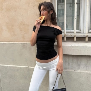Dettaglio del top nero aderente a spalle scoperte con pantaloni bianchi svasati