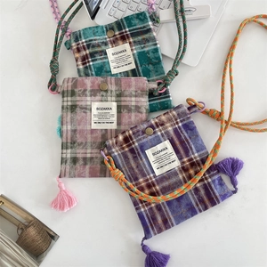 Close-up of checkered crossbody bags with fringe tassels and woven drawstring straps