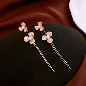 Boucles d'oreilles fleurs dorées avec pétales en zircon et perles sur fond de soie douce