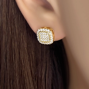 Macro shot of a gold-plated square stud earring with pavé-set diamonds on the ear