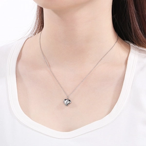 Macro close-up of a minimalist silver heart pendant on a polished metal chain for women