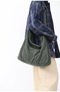 Detail of green corduroy crossbody bag texture and adjustable strap on model