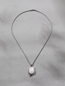 Detailed view of silver twist chain and oval pink gemstone pendant with metal inlay
