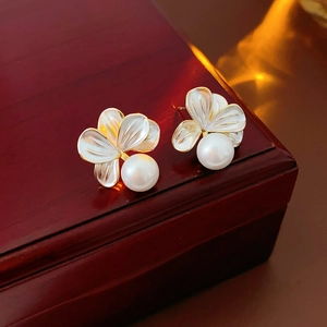Vue macro de boucles d'oreilles fleurs dorées et perles sur fond en bois sombre