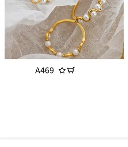 Dettaglio di un elegante anello dorato a onde con perle incastonate su tessuto bianco