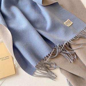 Detail of double-sided cashmere scarf in fog blue and beige with fringe and brand label