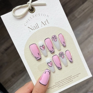 Faux ongles faits main style pop art rose et blanc avec motifs de cœur sur présentoir