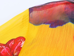 Close-up of yellow floral chiffon fabric with vertical pleated texture and dye prints