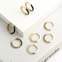 Detail of gold-plated hoop earrings with black and white enamel and zircon inlays