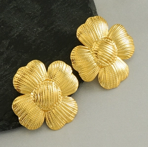 Détail macro de boucles d'oreilles fleur dorées avec textures sur fond de pierre