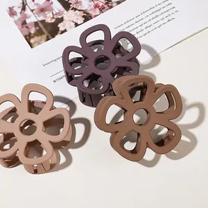 Three matte floral hair claws in beige, purple, and mocha colors on a neutral background