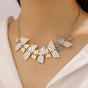 Macro shot of geometric mixed-metal triangle pendant with textured gold and silver finishes