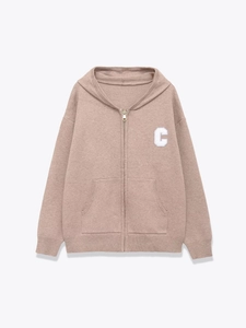 Detail of mauve knit zip-up hoodie featuring a white letter C patch and ribbed cuffs
