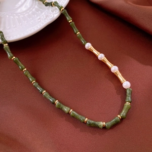 Vue détaillée du collier en acier doré avec perles de bambou vertes et perles blanches