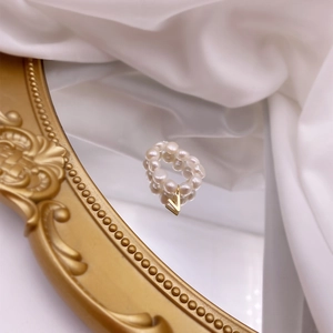 Macro shot of freshwater pearl ring with gold V pendant on vintage mirror