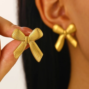 Detailed view of gold bow earrings showing delicate metal texture and professional wear effect