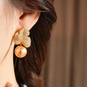 Close-up of model wearing clover pearl earrings with gold plating and sparkling zircon