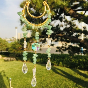 Detail of hanging suncatcher with green crystal chips and clear faceted pendants in nature