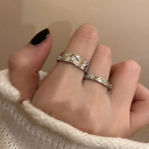 Close-up of minimalist silver zircon open rings with wavy and chain textures
