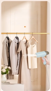 Close-up of portable blue garment steamer emitting continuous steam on hanging clothes
