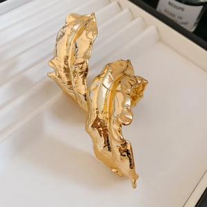 Close-up of golden metallic leaf arm cuff with artistic wrinkled texture and high shine