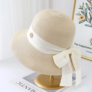 Elegant beige straw sun hat with white chiffon ribbon and bow on a gold metal stand