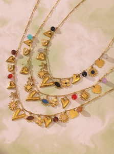 Close-up of layered 18k gold necklaces with colorful beads and heart-shaped pendants