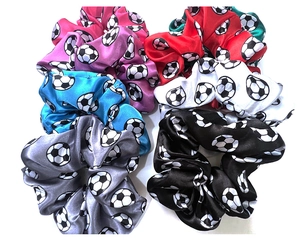 Detail view of six colorful satin hair scrunchies with soccer ball patterns on white background