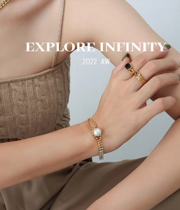 Detailed view of a gold-plated pearl bracelet and zircon rings worn on a female wrist