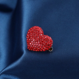 Exquisite red heart rhinestone brooch with sparkling crystals on dark blue silk background