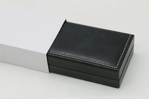 Detail of rectangular black PU leather watch box with white stitching and sleeve