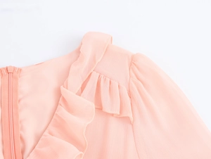 Detail of pink chiffon dress featuring a back zipper and elegant ruffle shoulder design