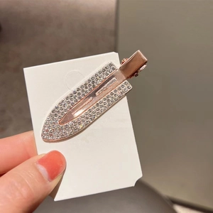 Detailed view of a rose gold rhinestone hair clip with sparkling crystals on white card