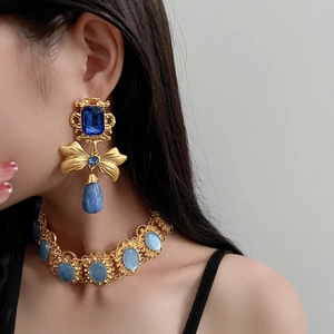 Close-up of vintage bow and water drop earrings set with blue gems on a model