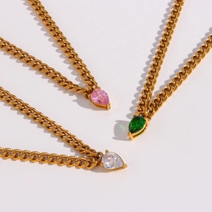 Detail of tear-drop gemstone pendants in pink, green and white on thick gold Cuban link chains
