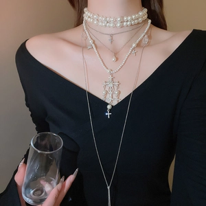 Close-up of layered necklace set featuring pearls and silver cross pendants on a model