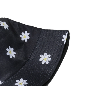 Close-up of black bucket hat featuring white daisy prints and high-quality fabric texture